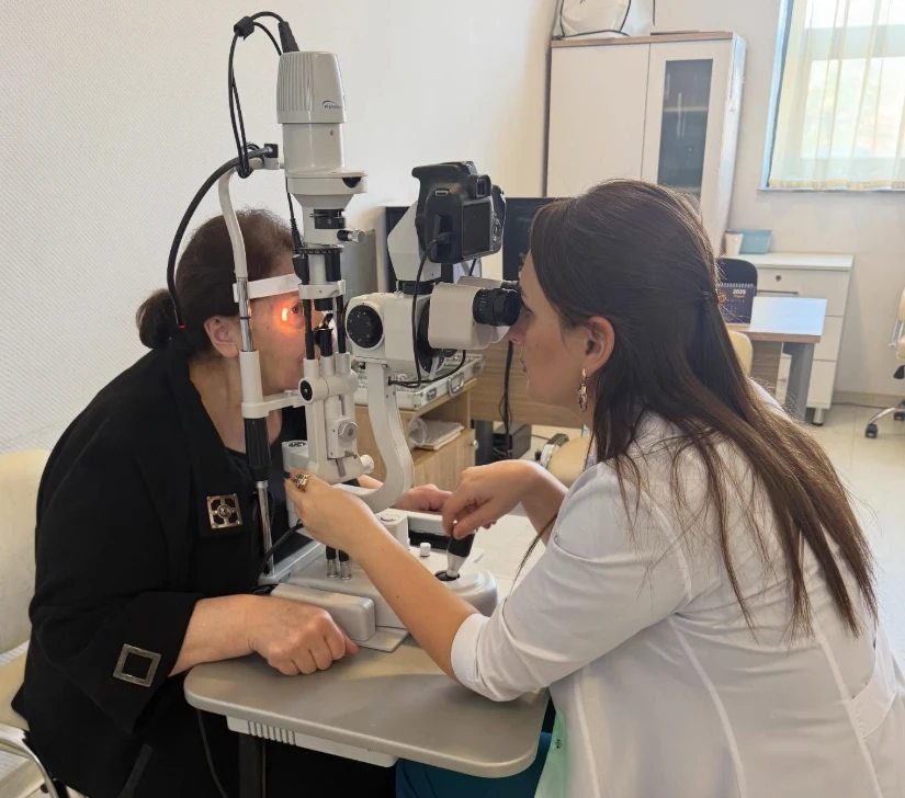 Oftalmoloq Saraxanım Kərimova yarıqlı lampa ilə pasiyentin gözünü müayinə edir